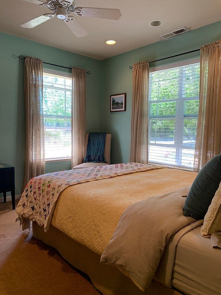 A bedroom with a bed , chair , and ceiling fan.