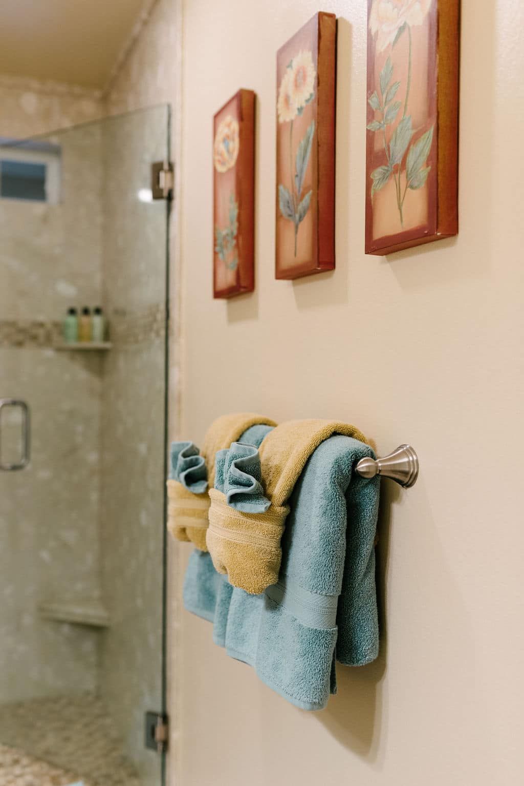 Two towels are hanging on a towel rack in a bathroom next to a shower.