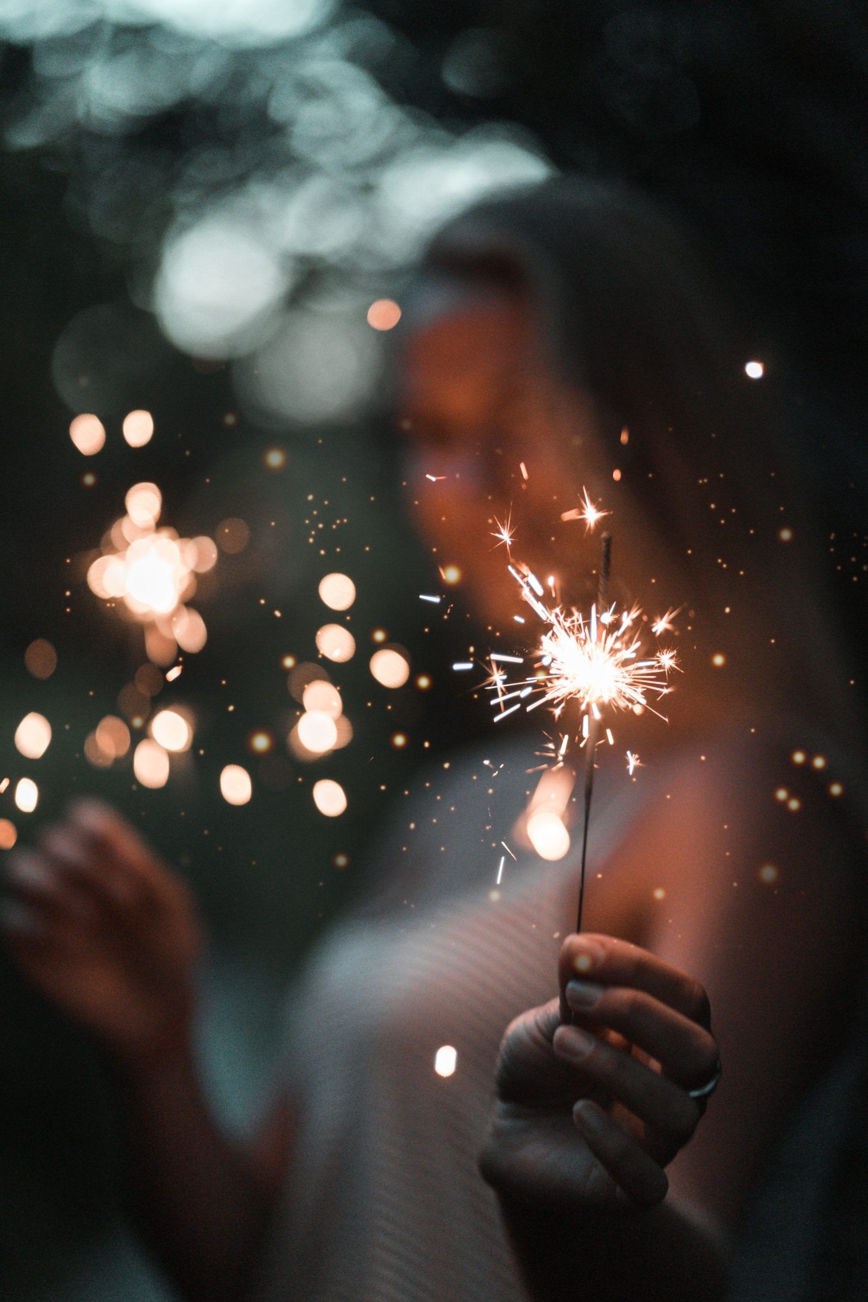 A woman is holding a sparkler in her hand.