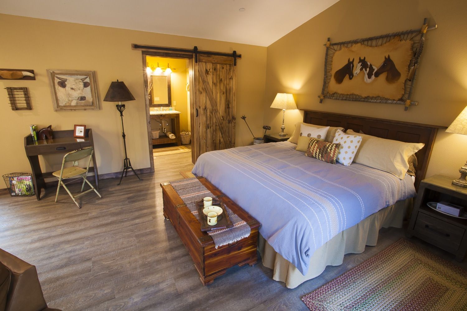 A bedroom with a king size bed and a sliding barn door leading to a bathroom.