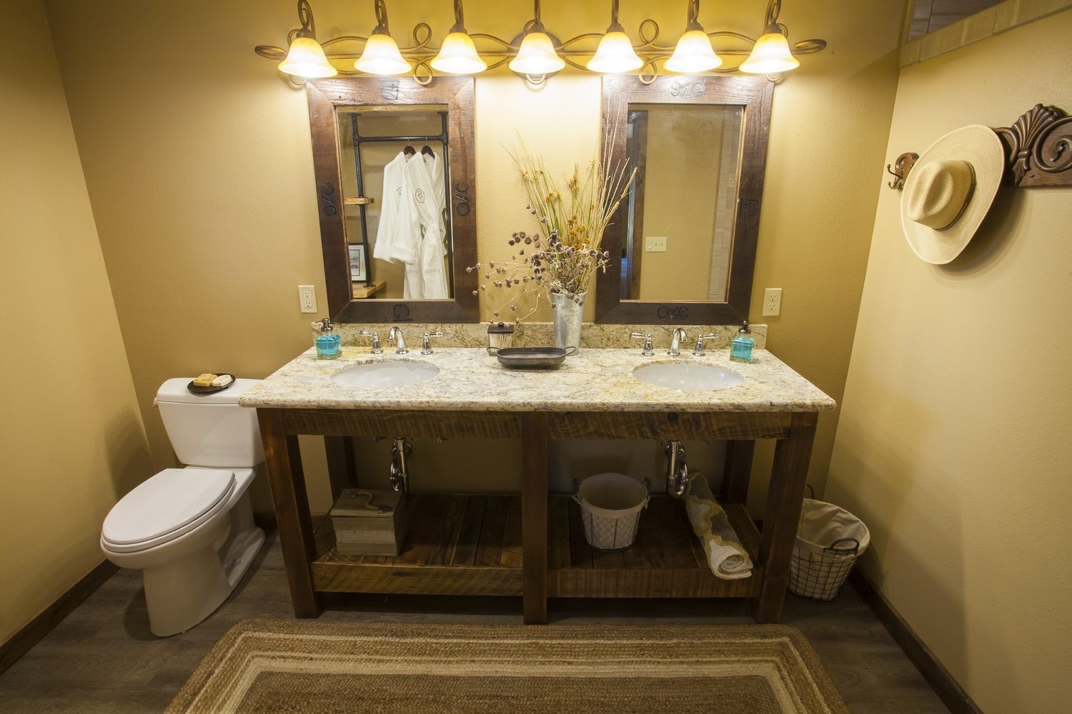 A bathroom with two sinks , a toilet , and two mirrors.
