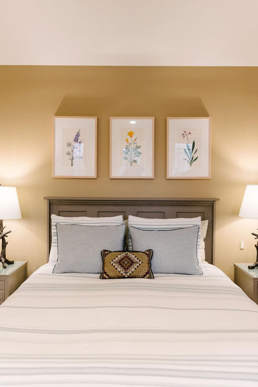 There are three paintings on the wall above the bed.