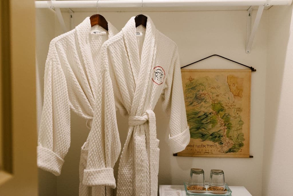 Two bathrobes are hanging on a shelf next to a map.