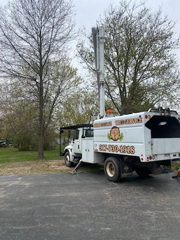 White tree service truck with a raised lift in a yard.