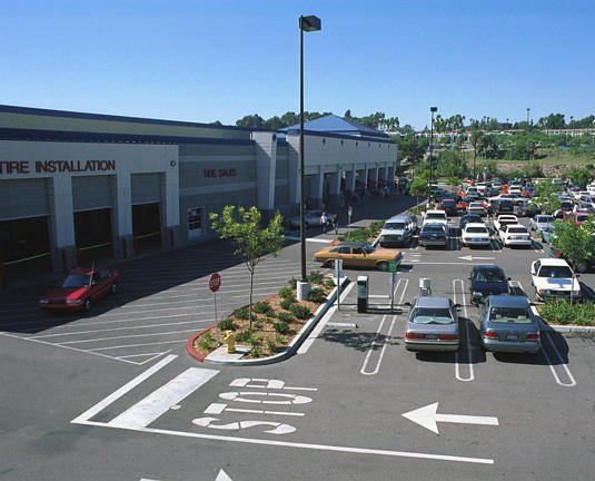 The first image of a Costco parking lot, with extensive asphalt paving. The second image is of a parking lot at a shopping mall with freshly paved asphalt.