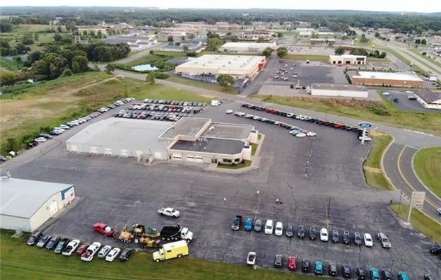 Aerial view of a commercial area with buildings, parked cars, and a looping roadway.