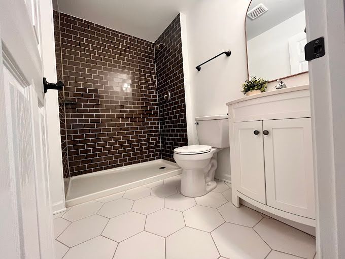 A bathroom with a toilet , sink and shower.