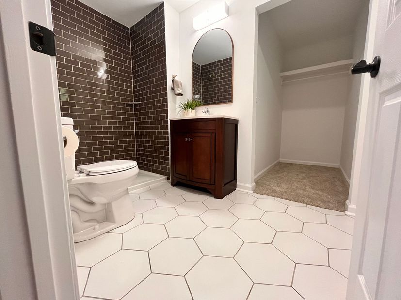 A bathroom with a toilet , sink , mirror and shower.