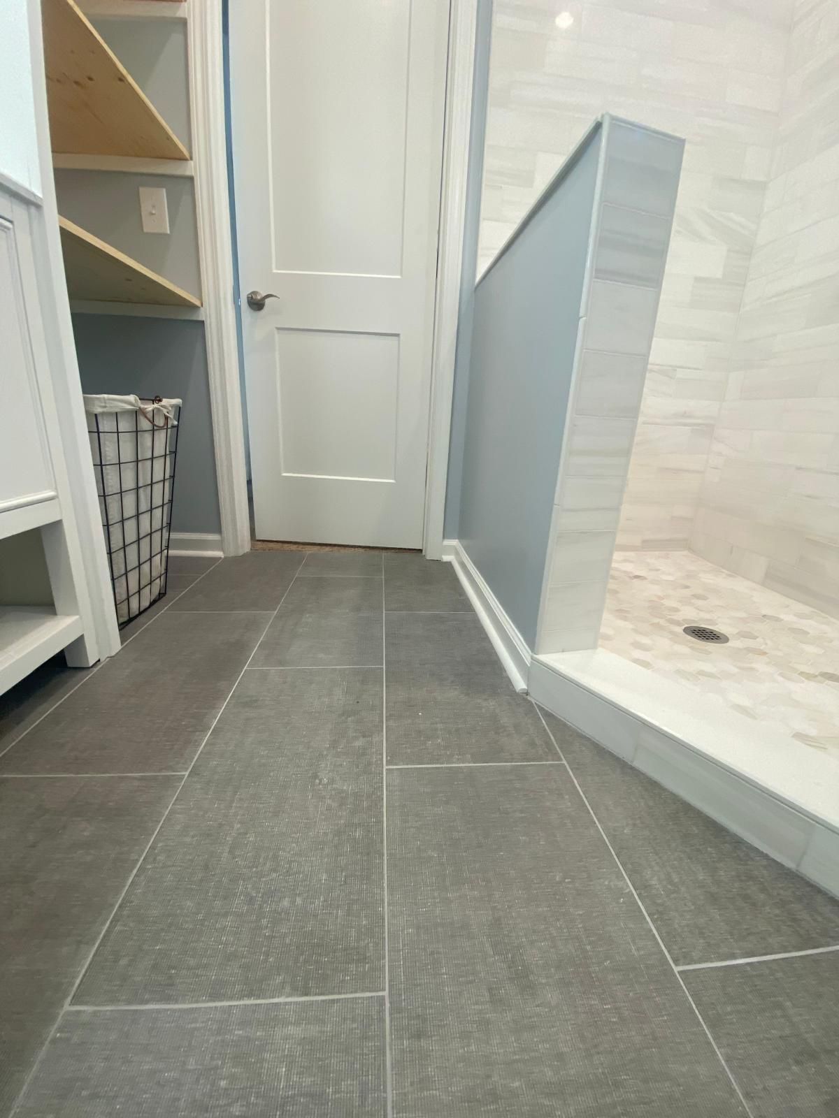 A bathroom with a walk in shower and a laundry basket.