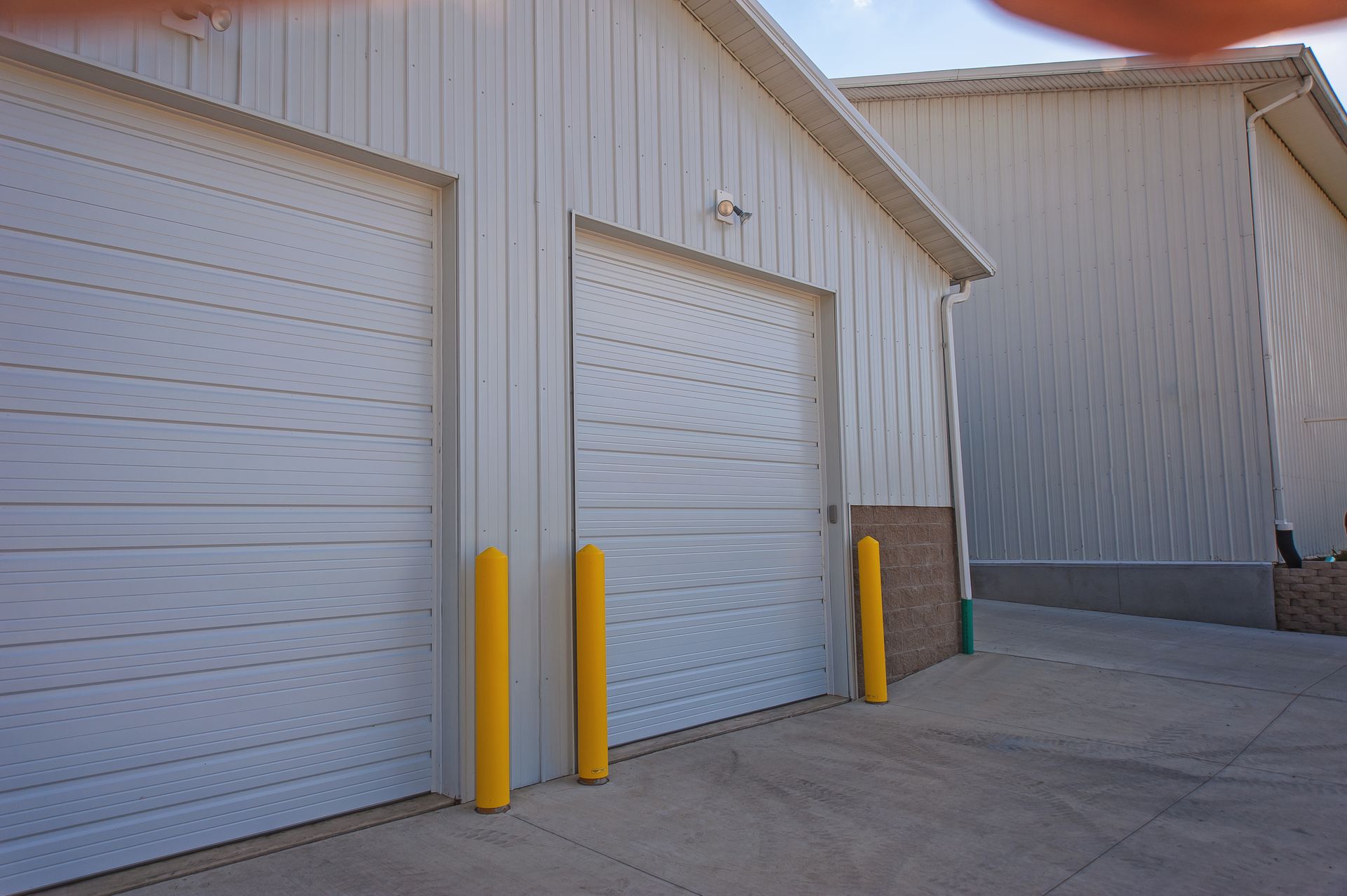 Two white garage doors with yellow poles in front of them