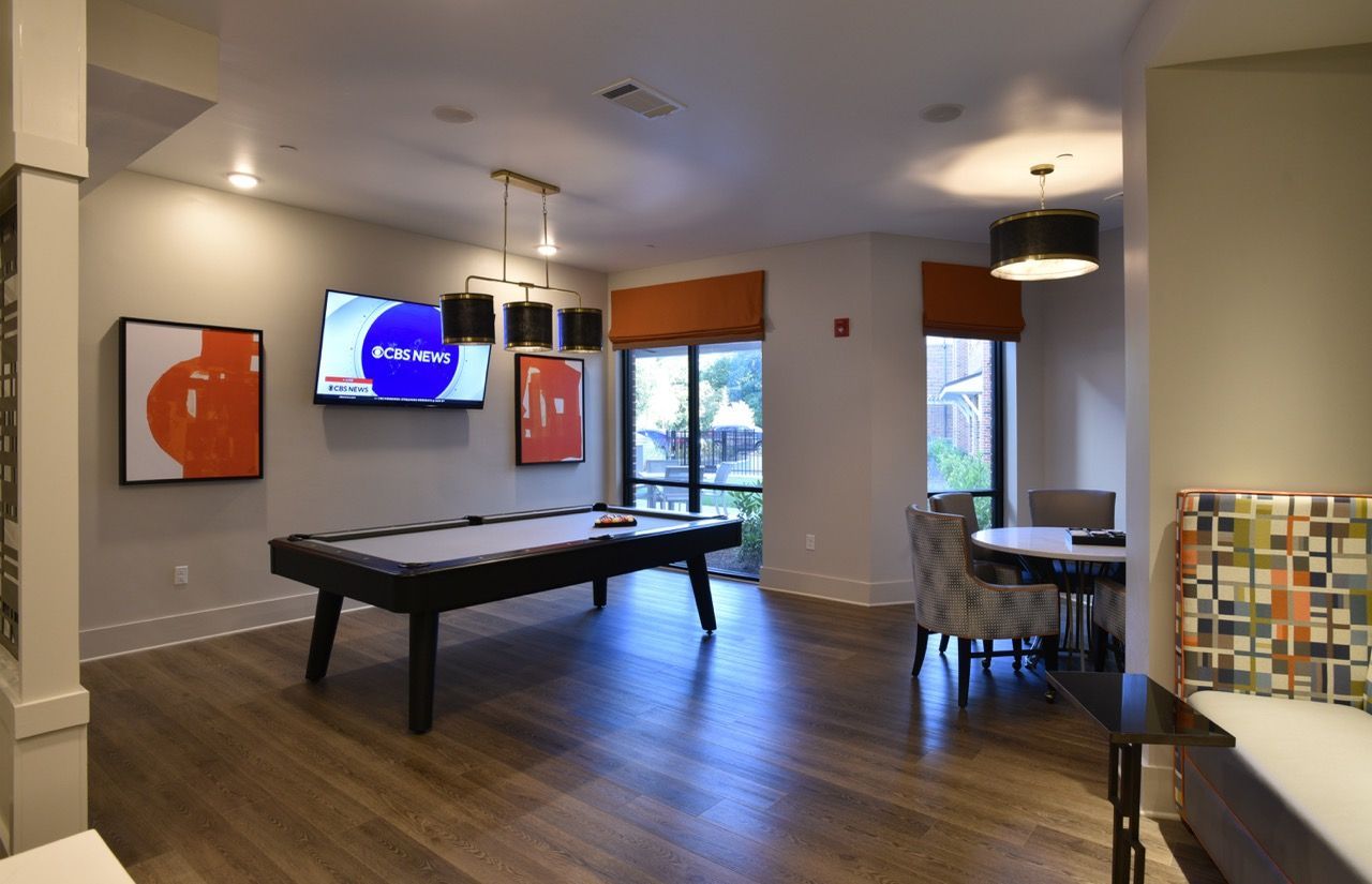 Indoor community recreation room with a pool table, seating area, and wall-mounted TV.