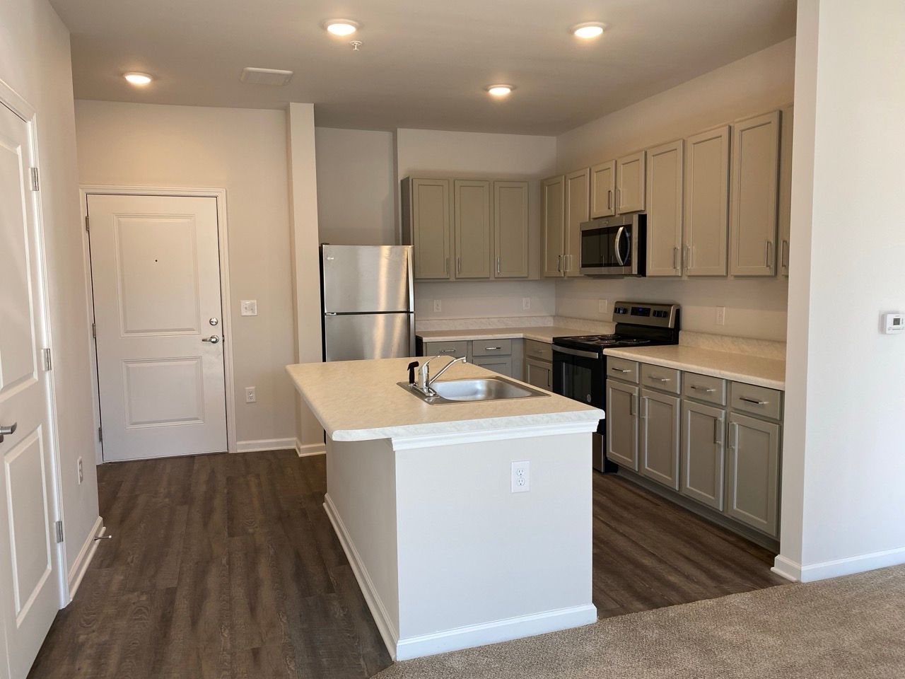 Open-concept kitchen with an island, light gray cabinets, and stainless steel appliances.