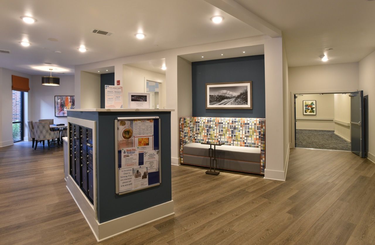 Interior apartment community lobby with a reception desk, mailboxes, and colorful seating area.