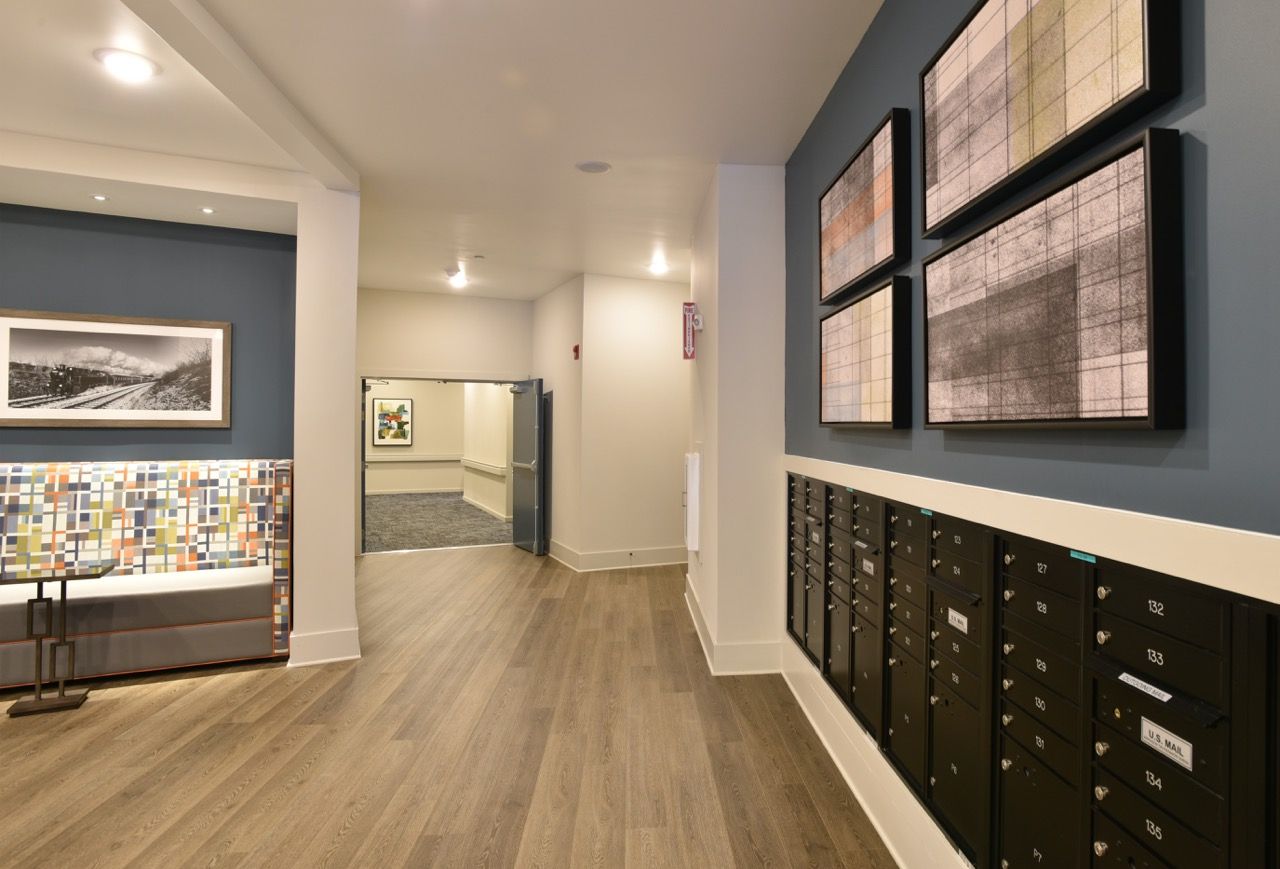 Lobby with mailboxes along the right wall, seating area and art on blue walls.