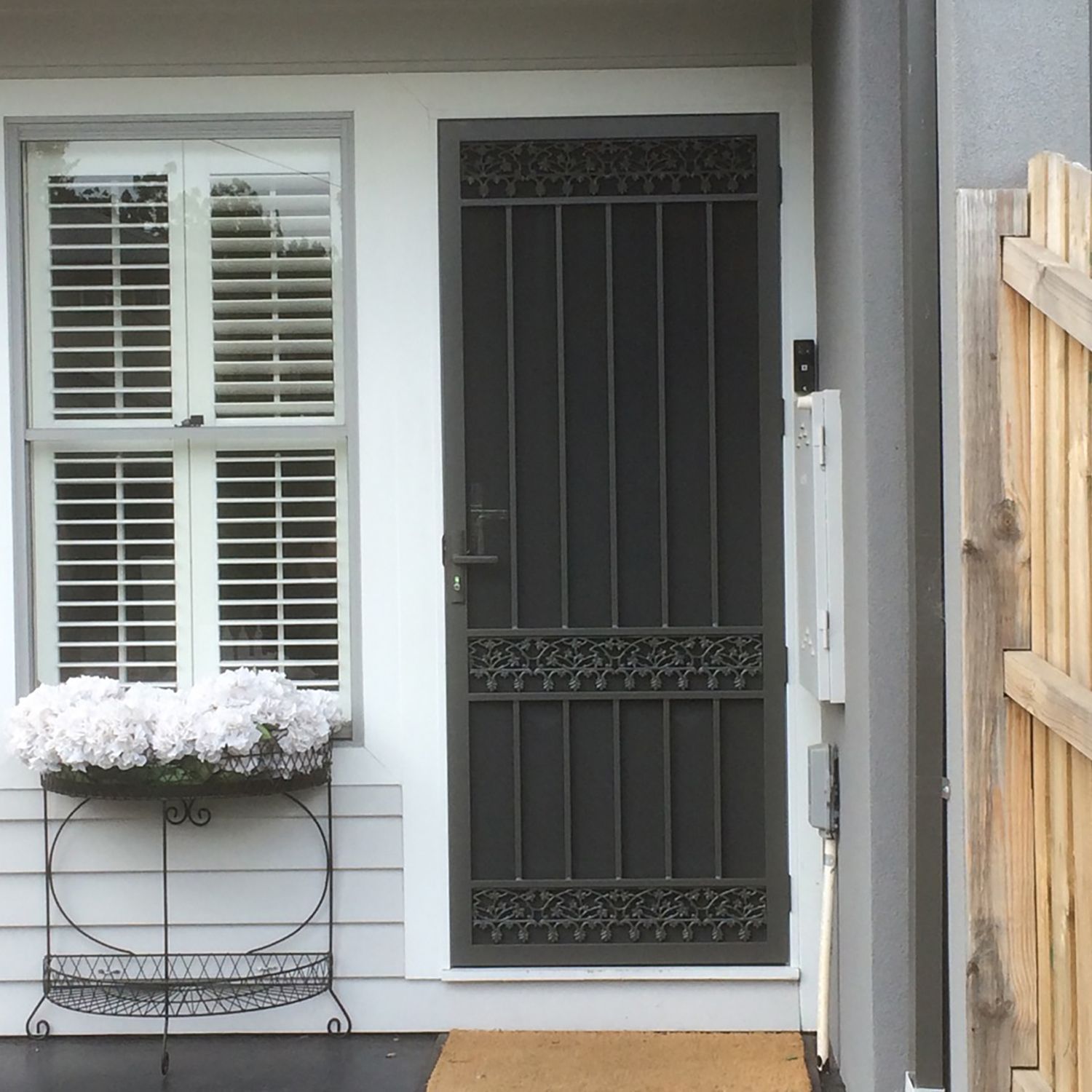 The front door of a house has a Premium Steel Security Door and a window with shutters