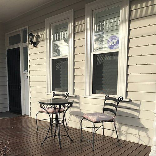 image is displaying two security window screens, there is a table and chairs on the porch of a house.