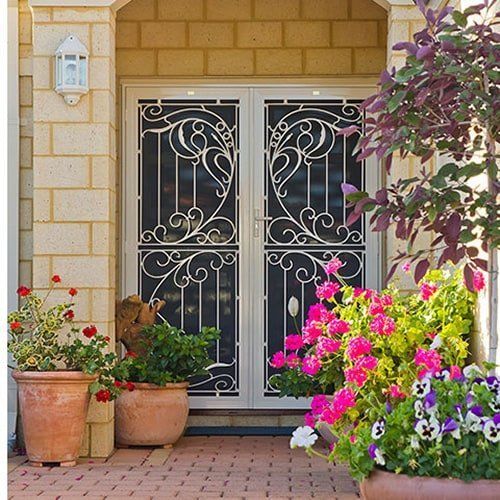 A front aluminium security door of a home with flowers in pots in front of it