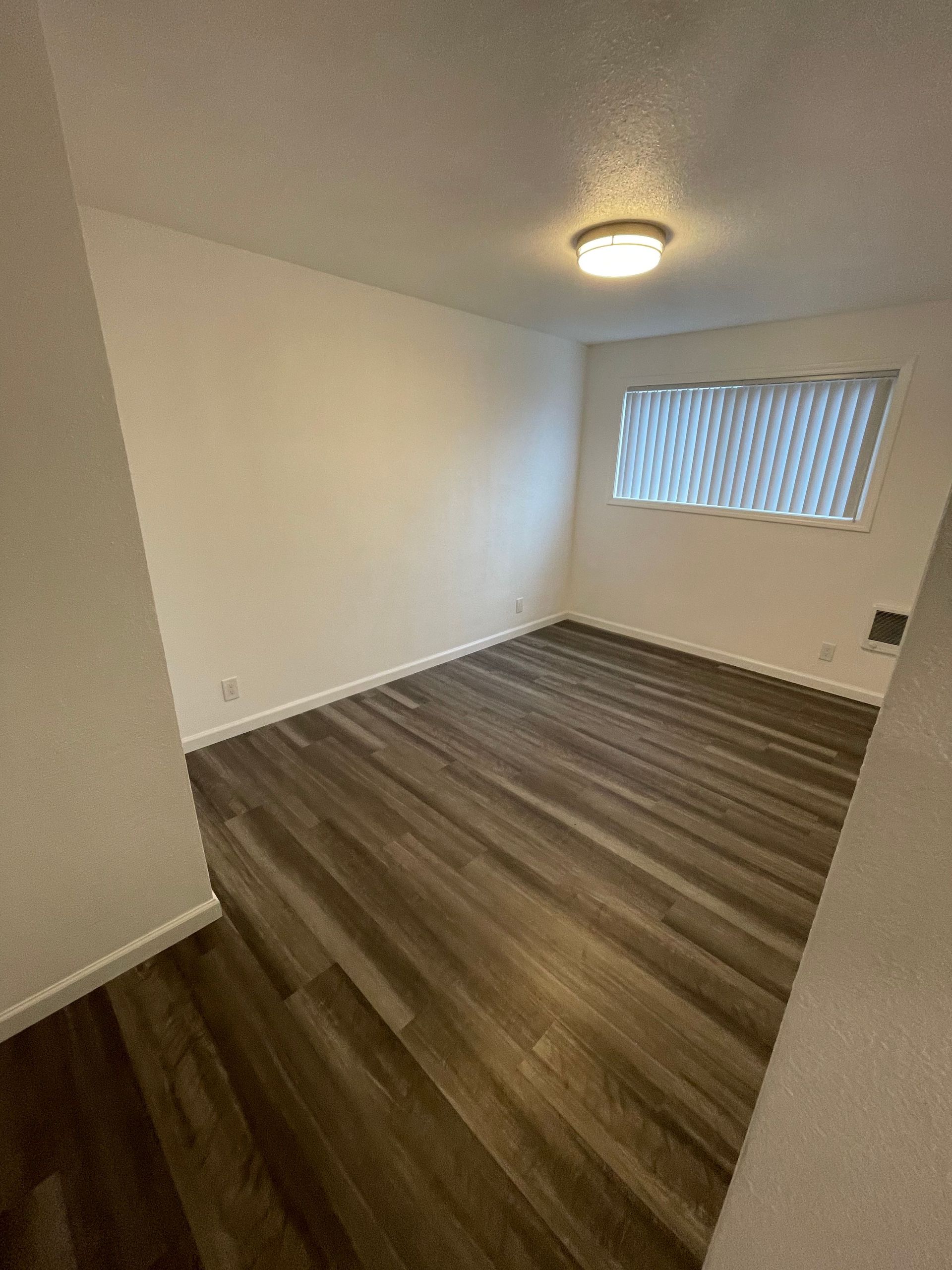 A living room with hardwood floors and a window.