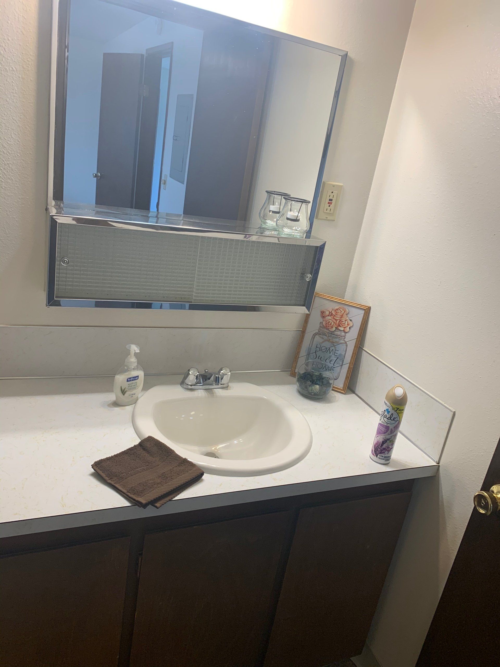 A bathroom with a sink , mirror and towel on the counter.