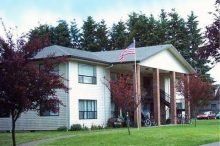A large white apartment building with an american flag flying in front of it.