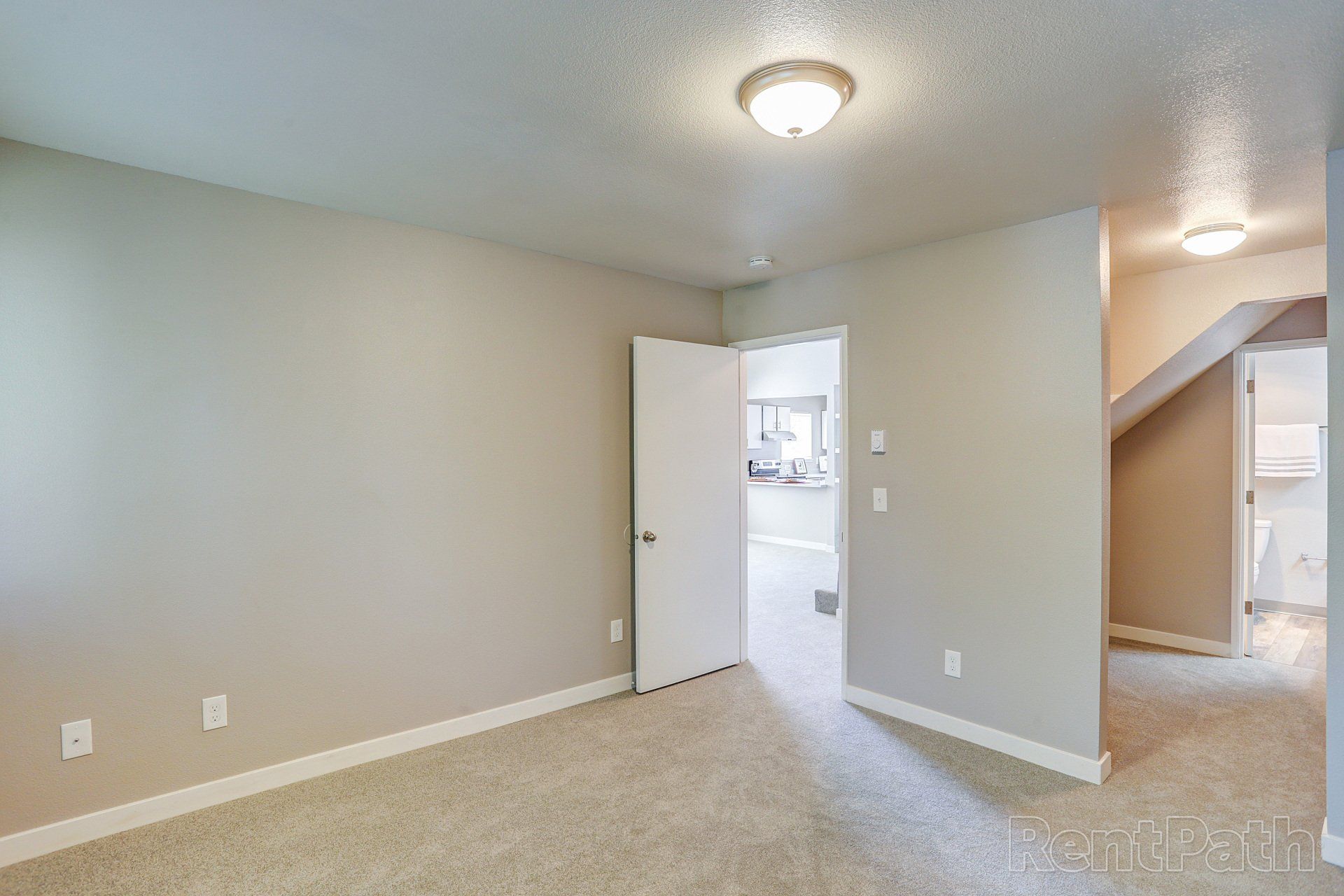 An empty room with a carpeted floor and a ceiling light.