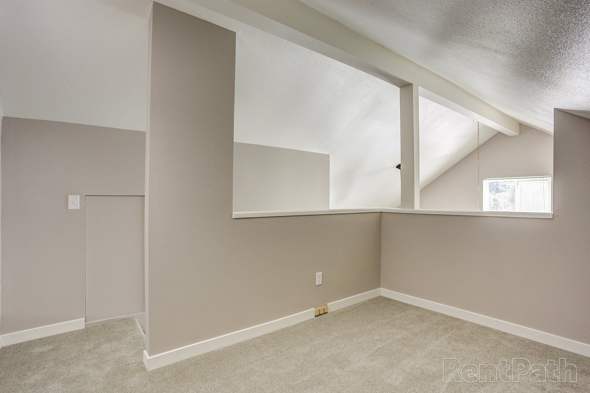 An empty room with a carpeted floor and a window.