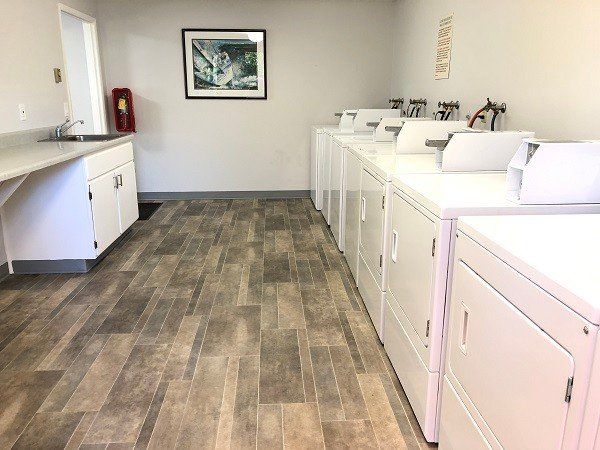 A laundry room with a lot of white washers and dryers