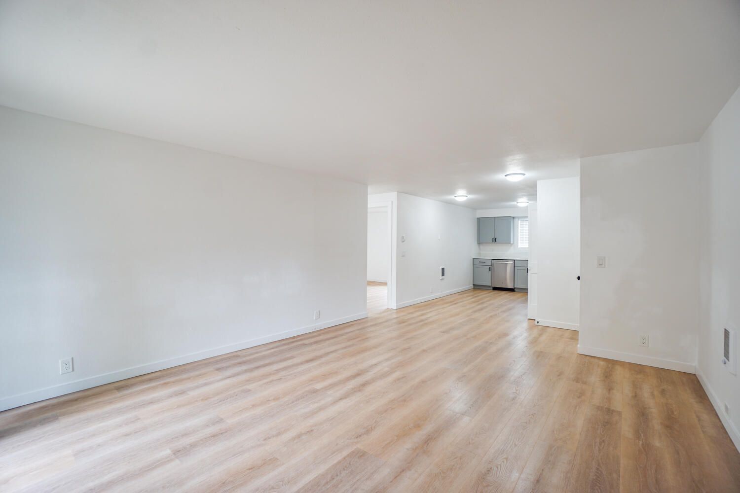 An empty living room with hardwood floors and white walls.