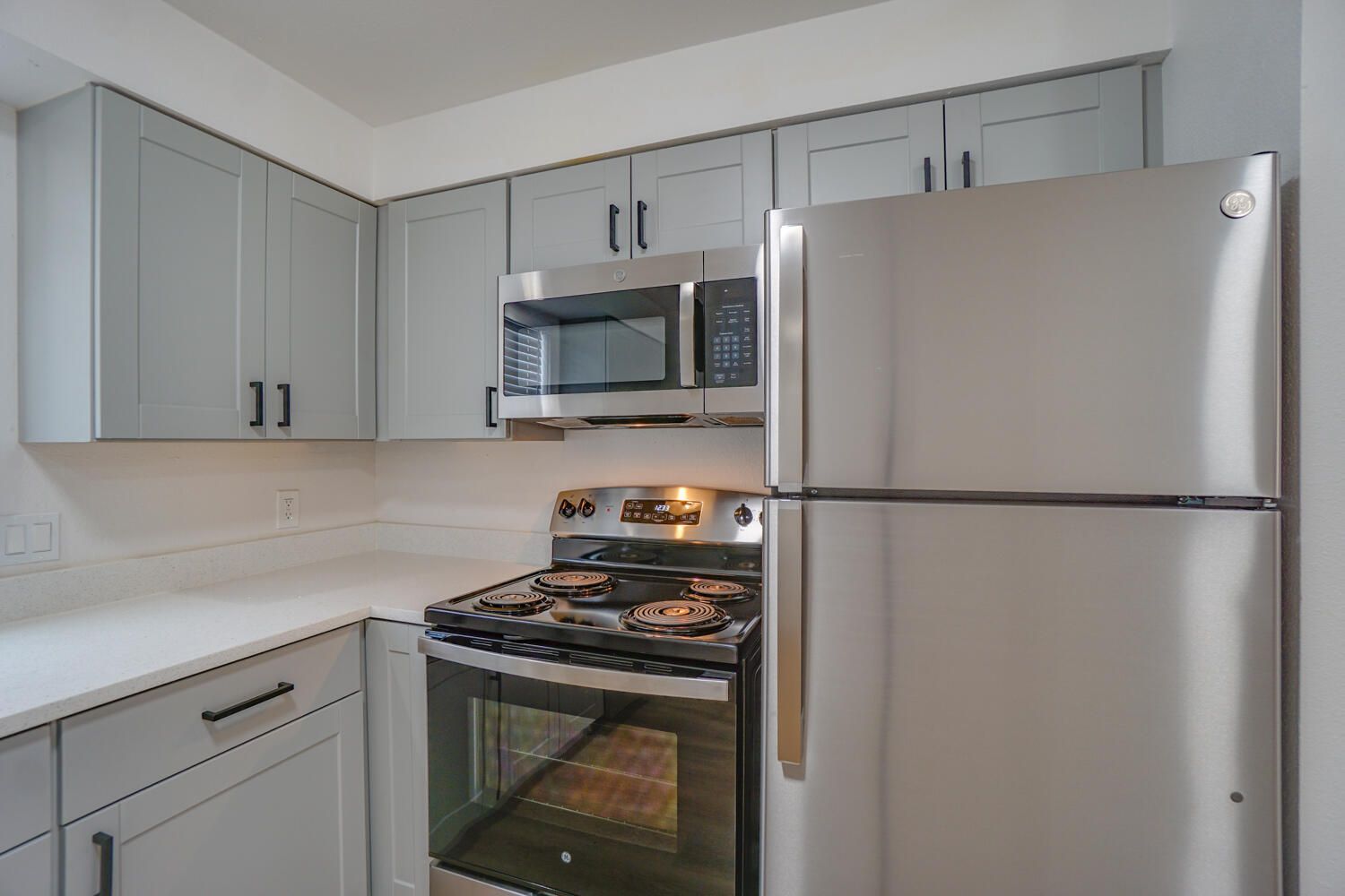 A kitchen with a stove , refrigerator , and microwave.