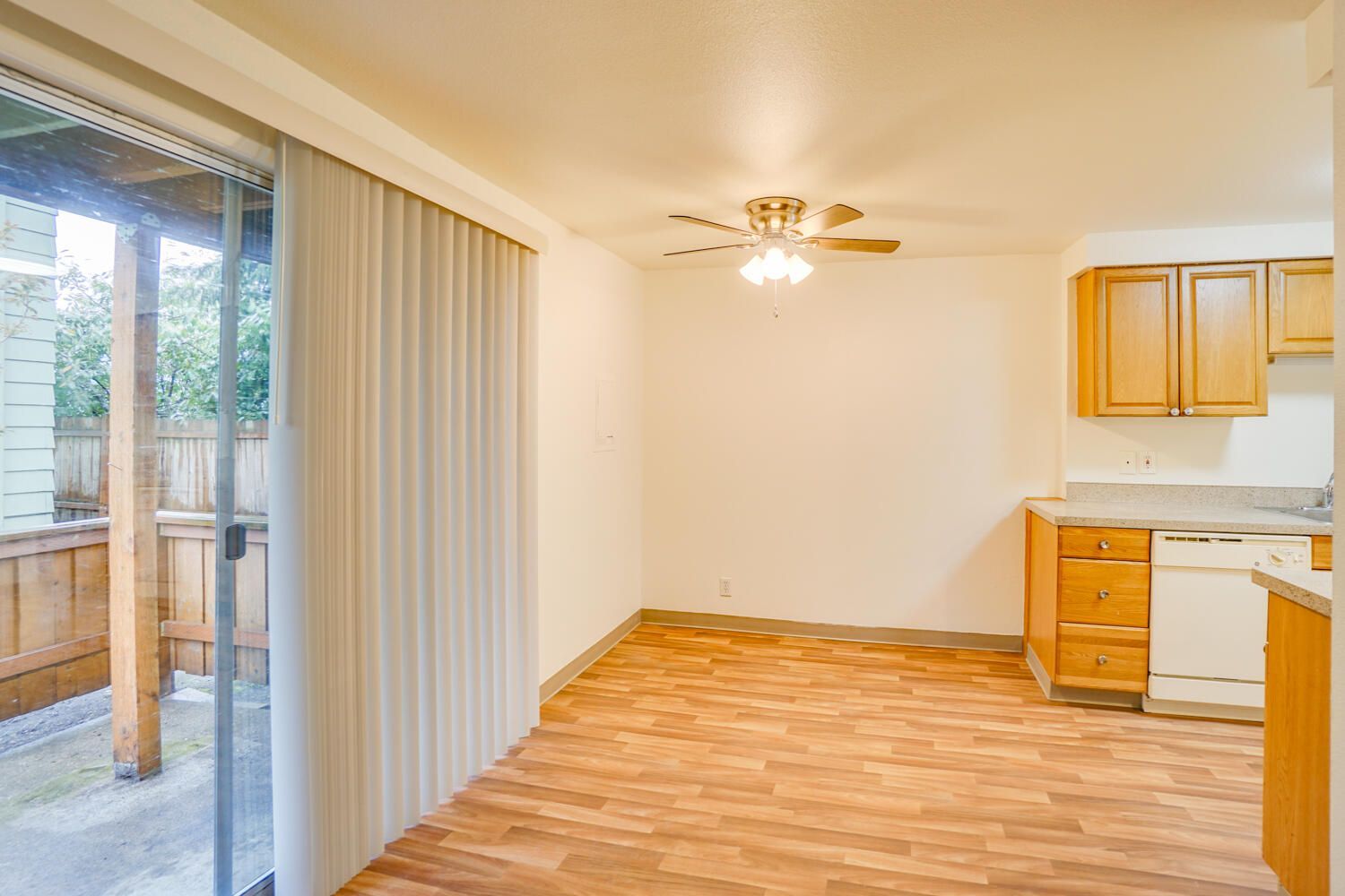 A kitchen and dining room in a house with sliding glass doors and a ceiling fan.