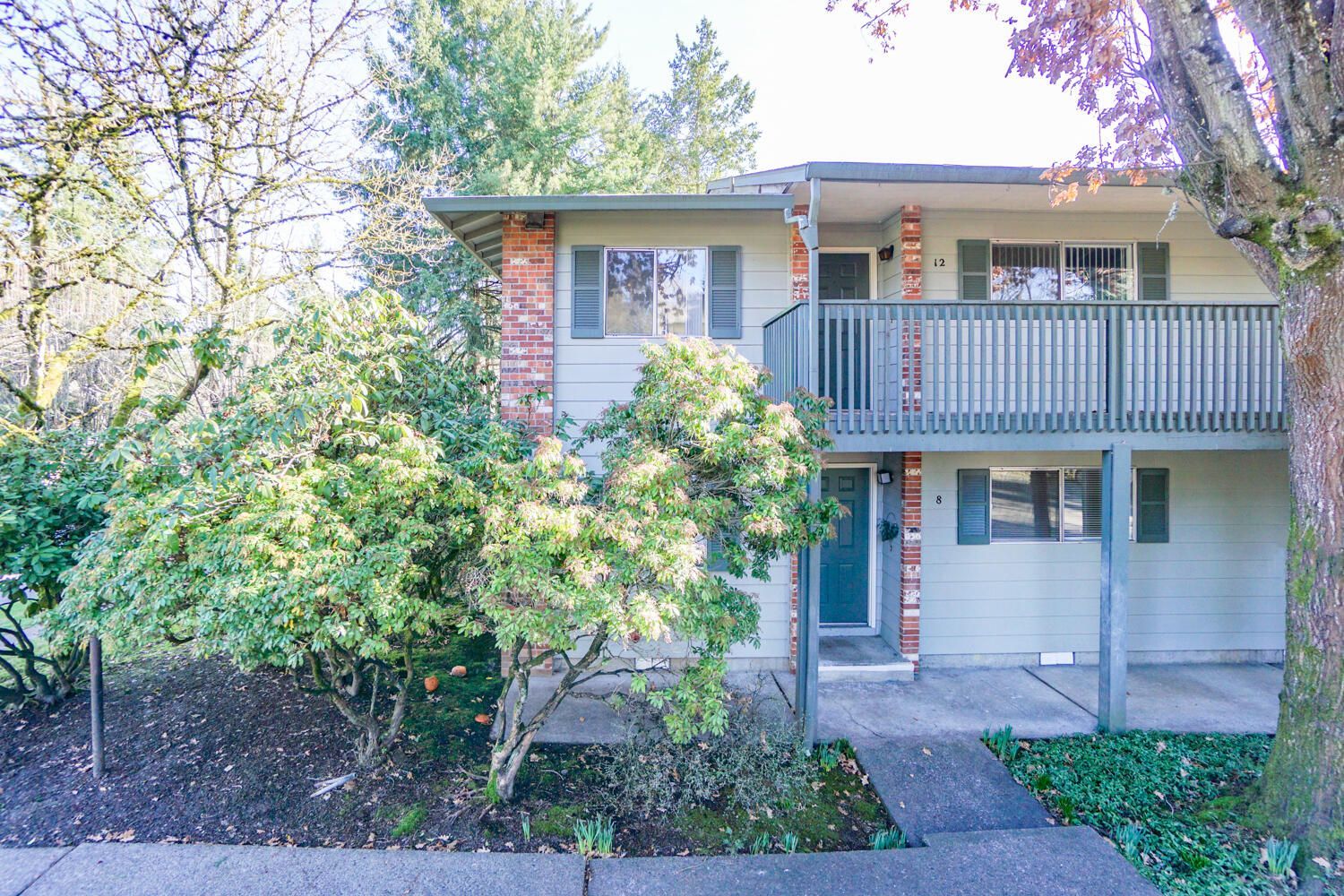 A house with a balcony and a tree in front of it