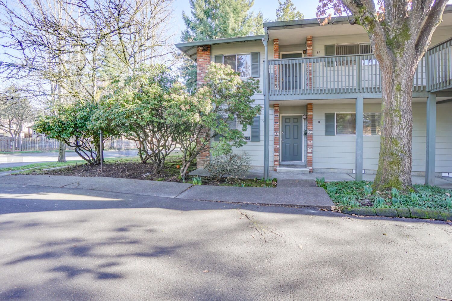 A white house with a balcony and trees in front of it