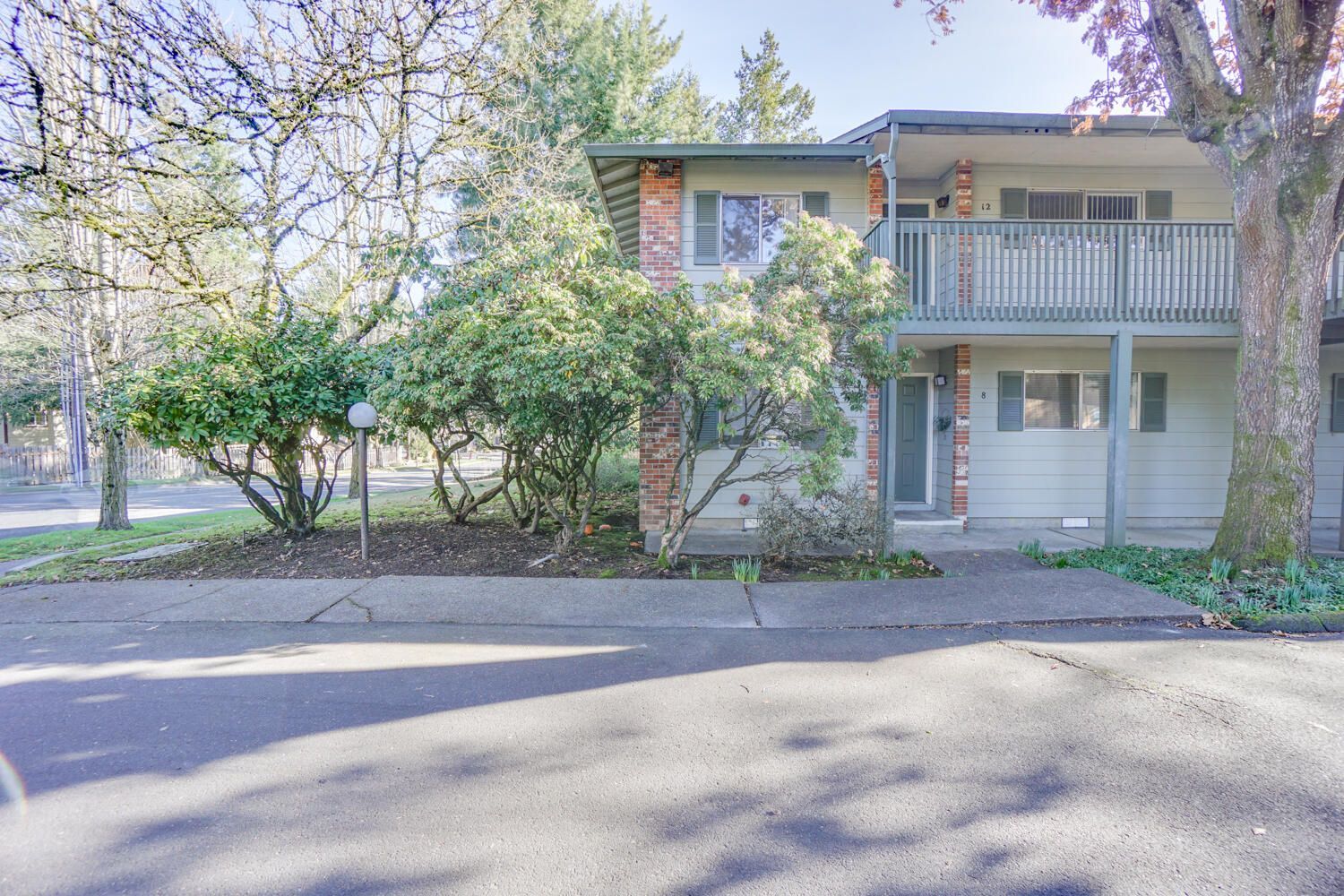 A white house with a balcony and trees in front of it