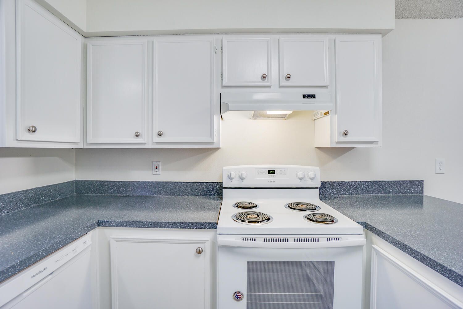 A kitchen with white cabinets and a white stove