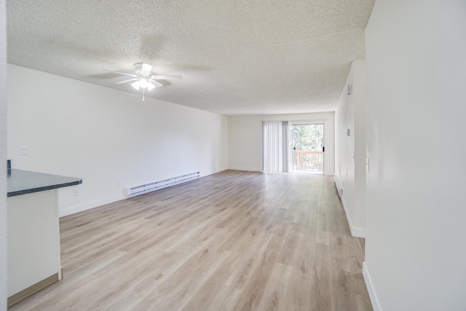 An empty living room with hardwood floors and a ceiling fan.