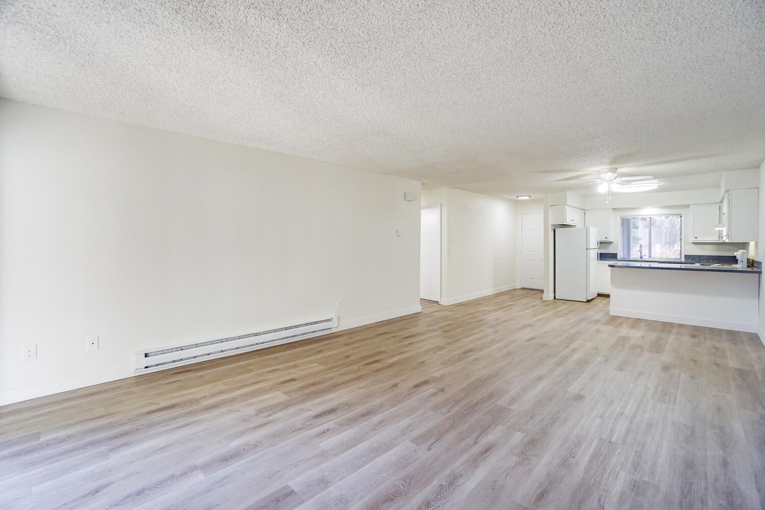 An empty living room with hardwood floors and white walls.