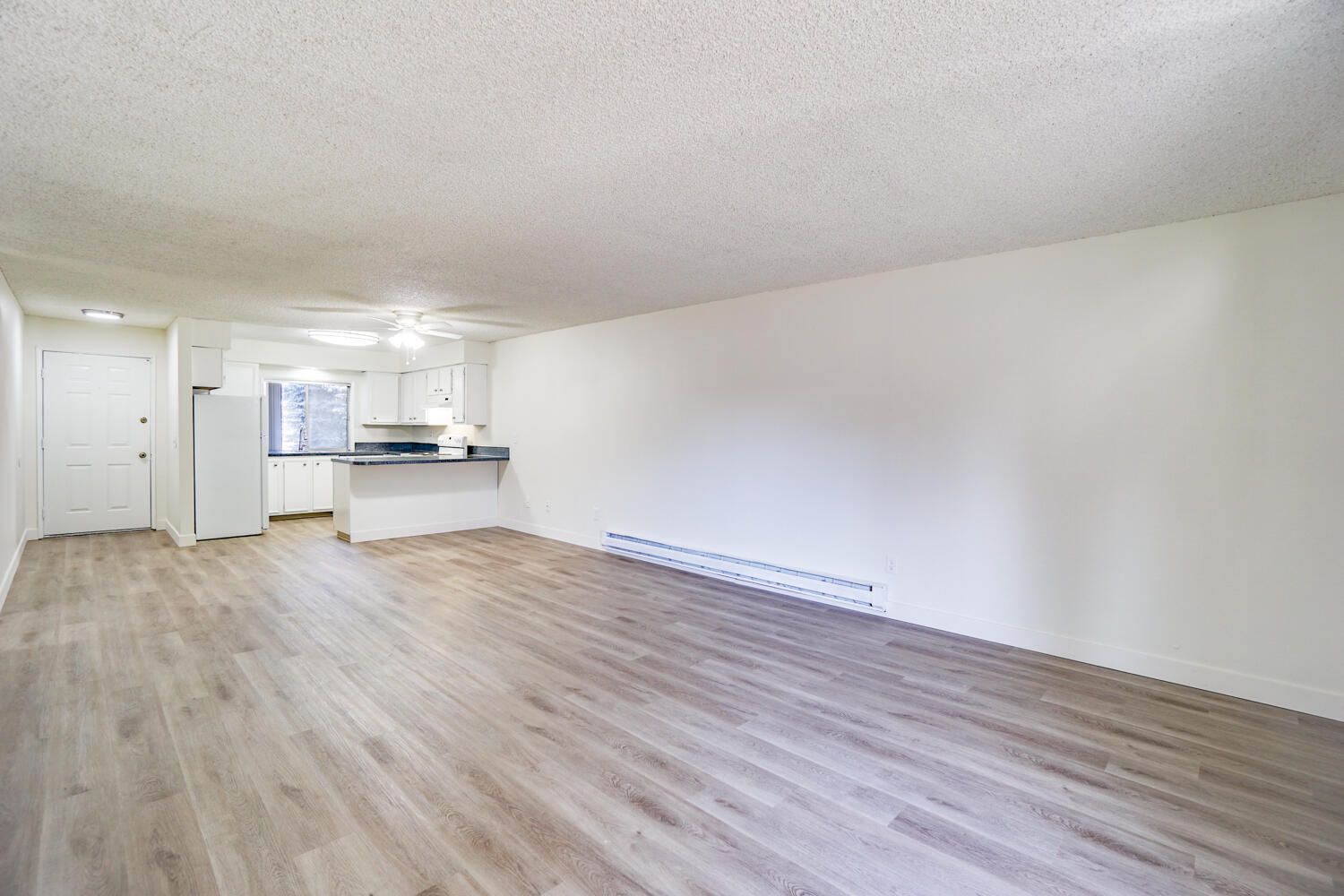An empty living room with hardwood floors and white walls.