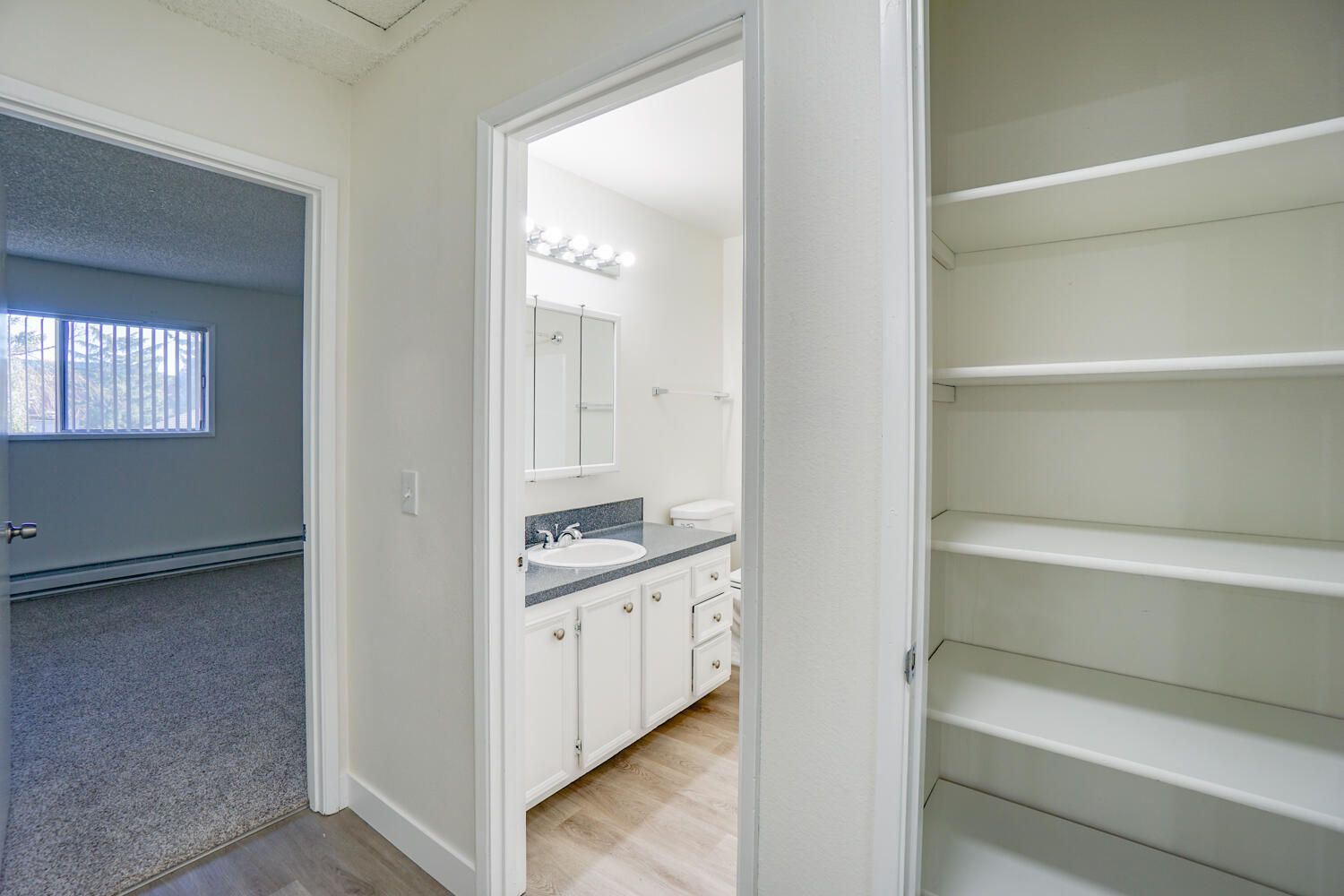 A hallway leading to a bathroom with a sink and mirror.