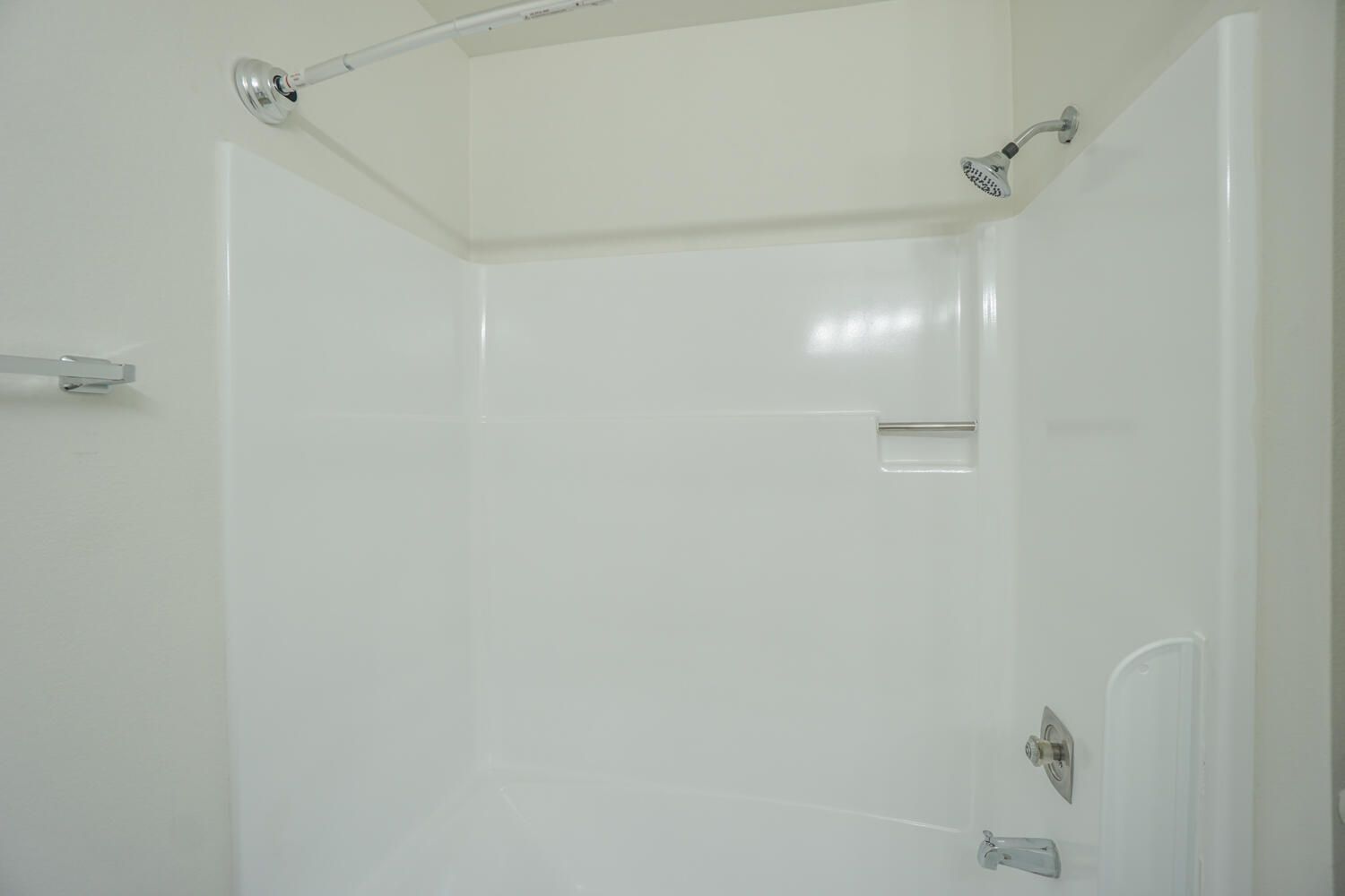A white shower stall with a shower head in a bathroom.