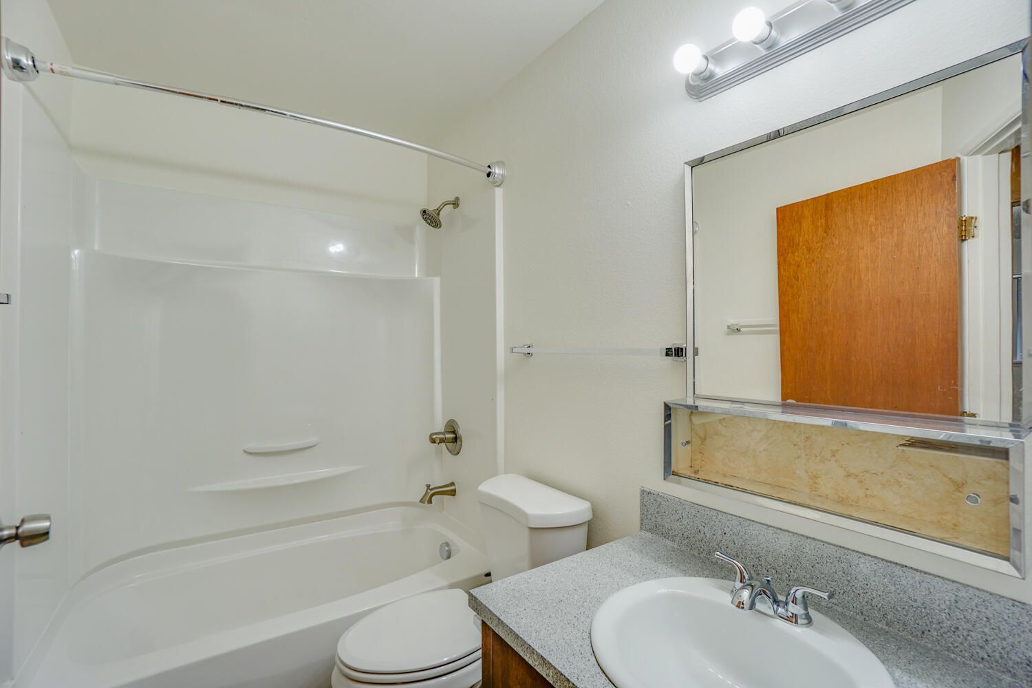 A bathroom with a tub , toilet , sink and mirror.