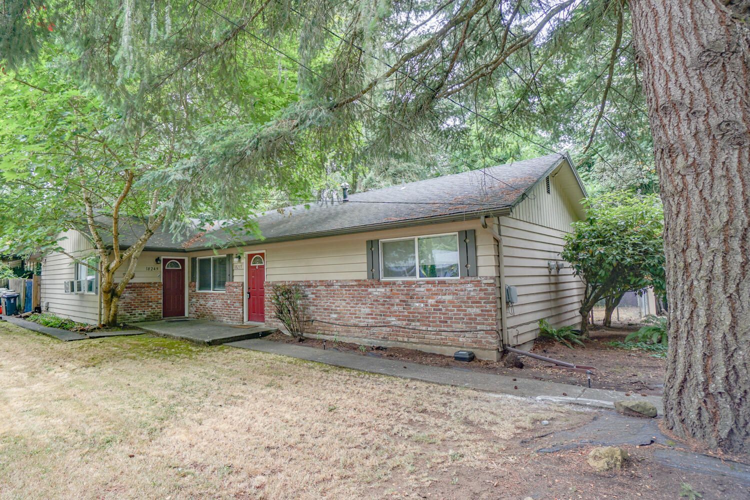 A small house with a red door and a tree in front of it.
