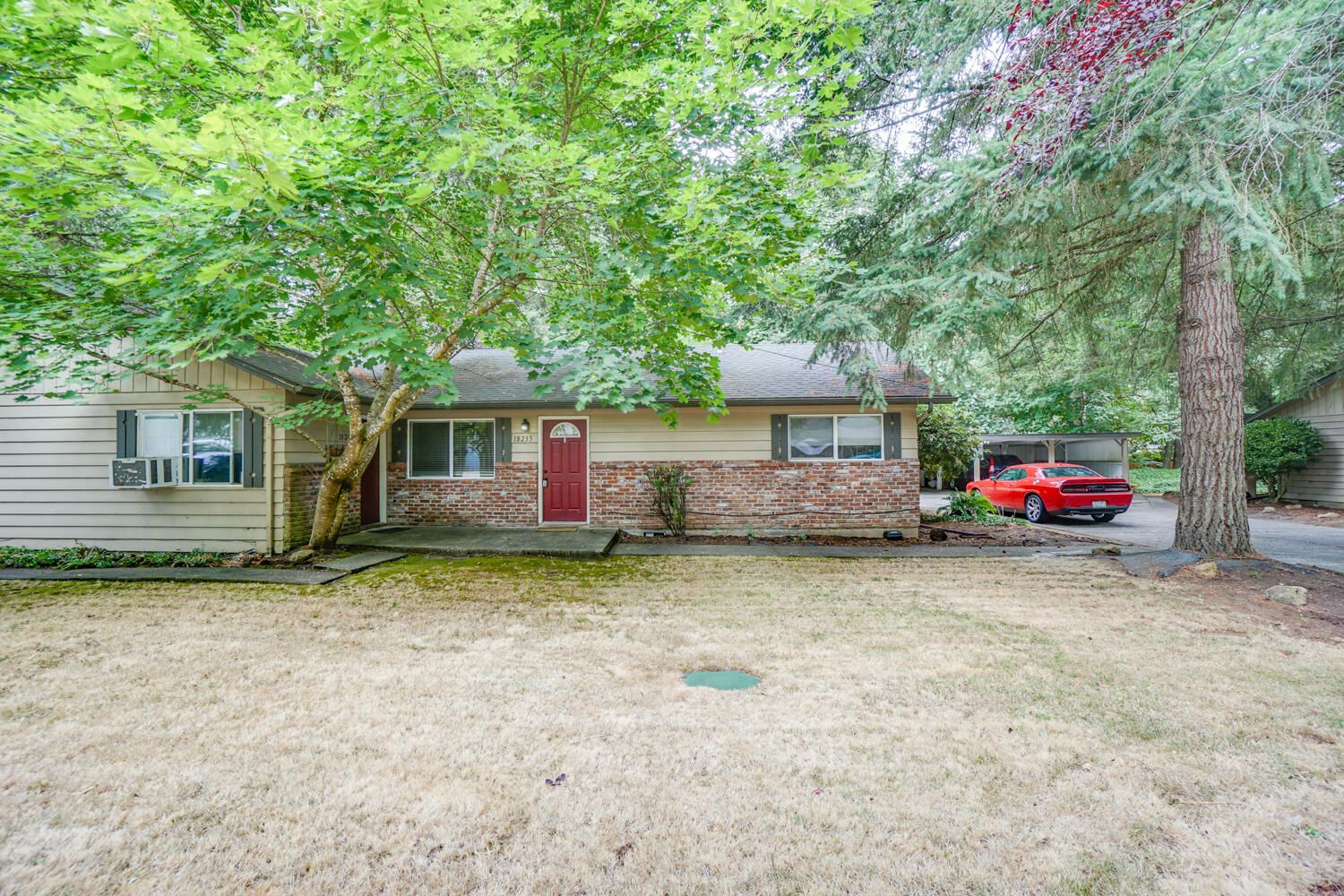 A house with a red car parked in front of it.