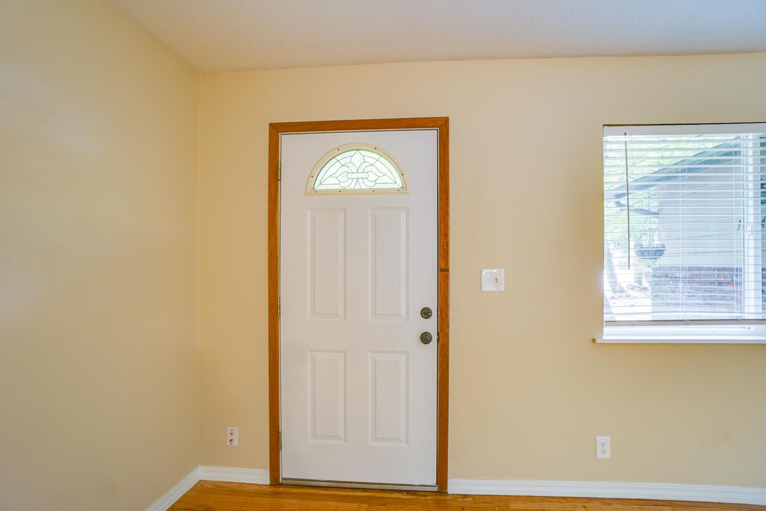 An empty room with a white door and a window.