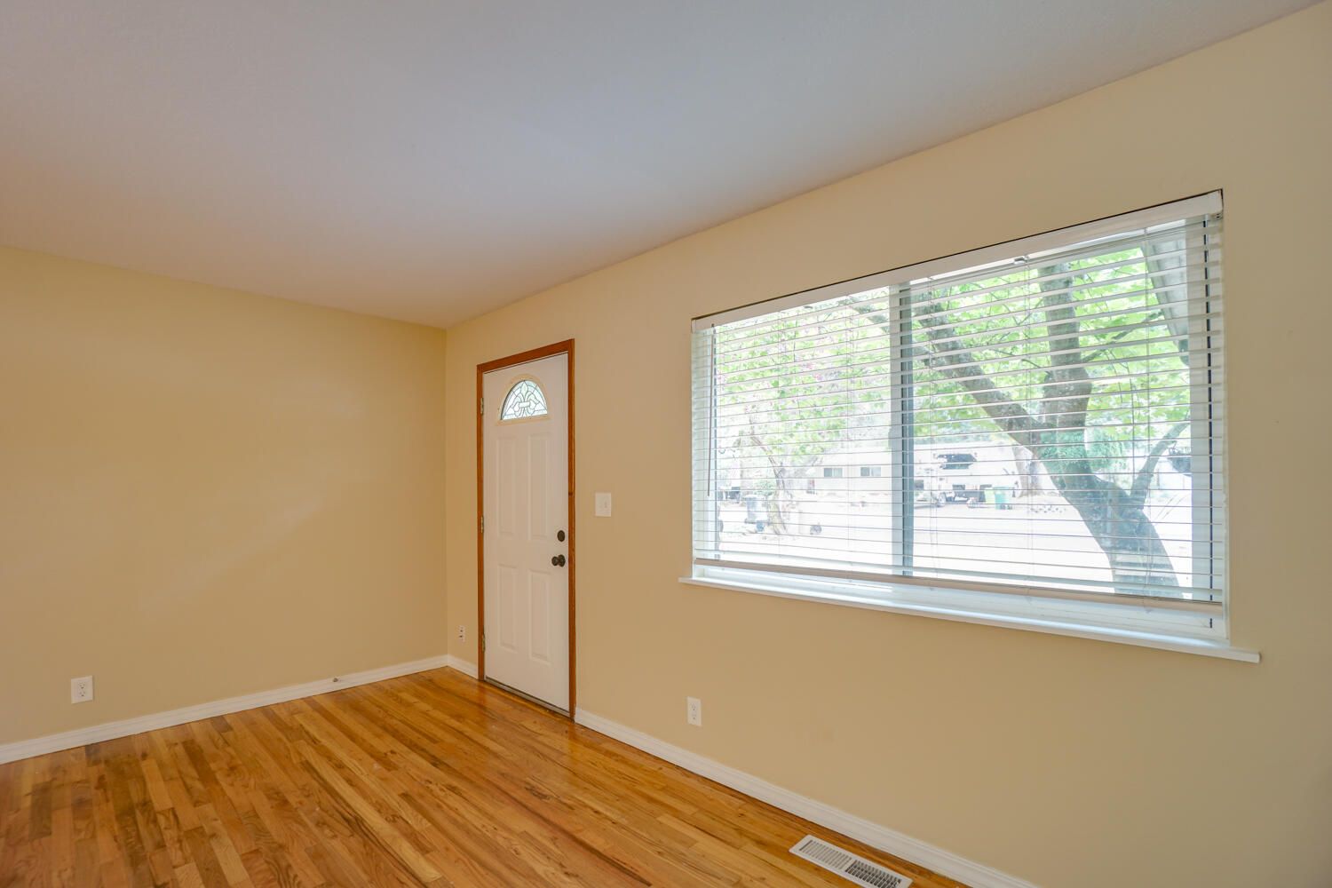 An empty living room with hardwood floors and a window.