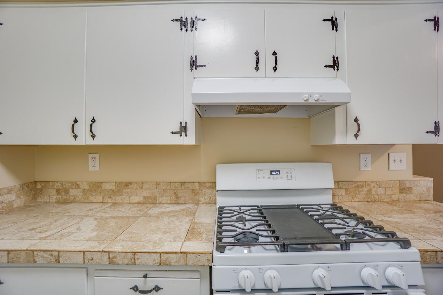 A kitchen with a stove and a hood above it