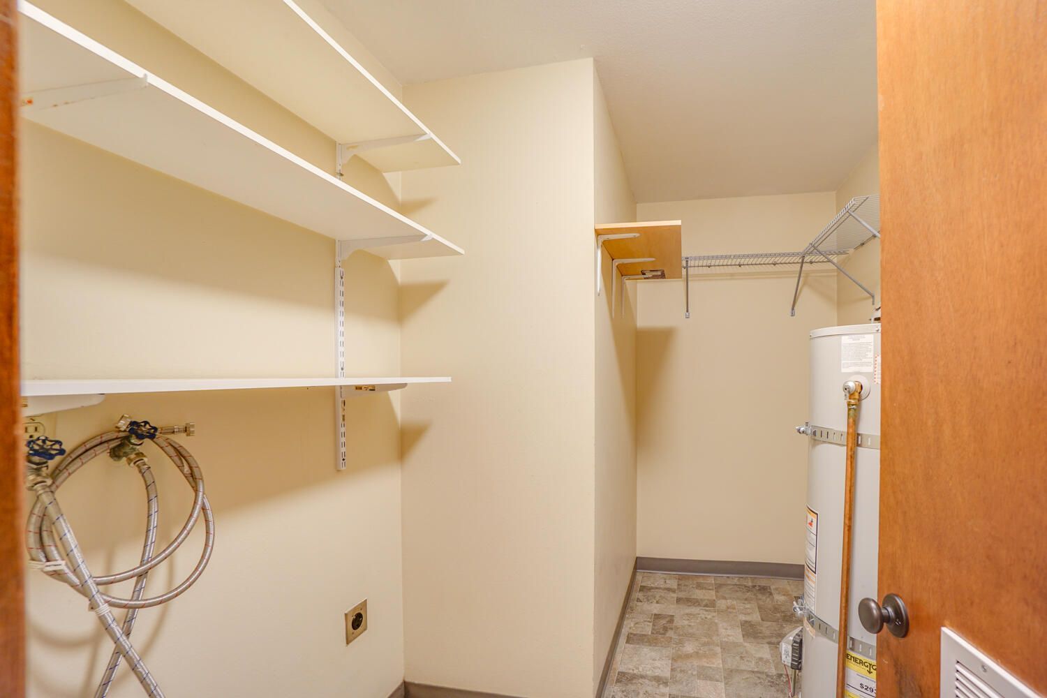 A laundry room with a washer and dryer and shelves.