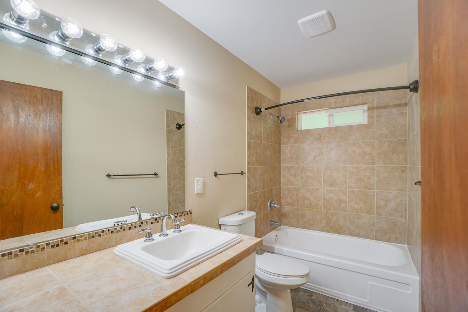 A bathroom with a sink , toilet , tub and mirror.