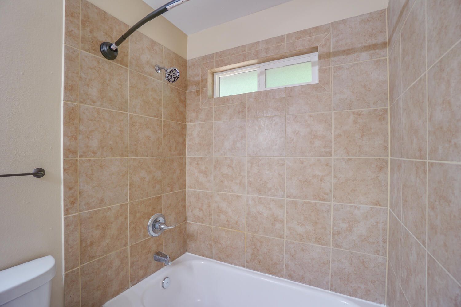 A bathroom with a tub , shower , toilet and window.