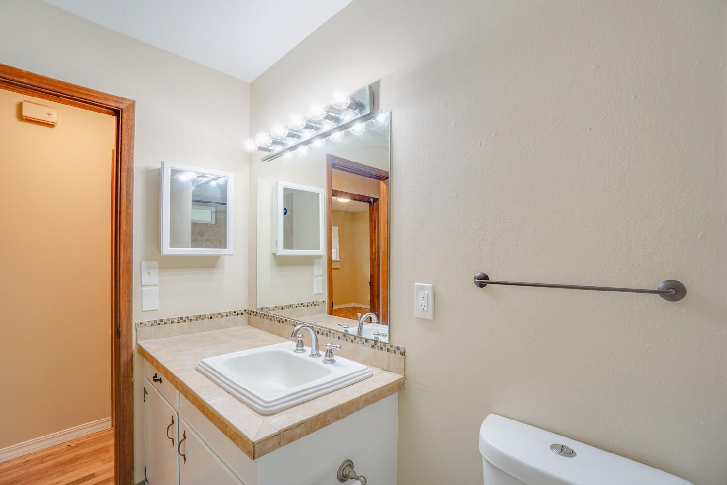 A bathroom with a sink , mirror and toilet.