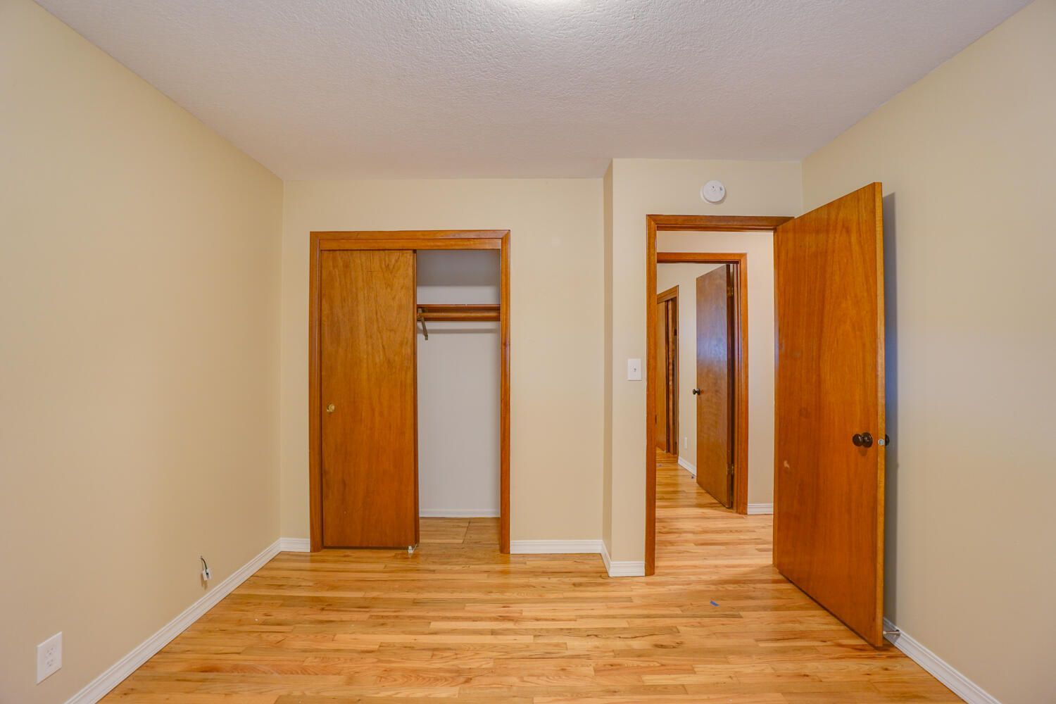 An empty bedroom with hardwood floors and a closet.